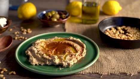 Warm,-low-angle-slide-to-the-left-showing-middle-eastern-food-spread-of-olives,-pine-nuts,-hummus,-feta-and-ouzo