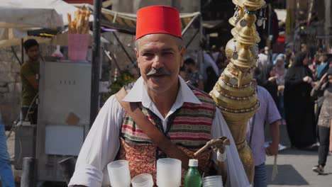Mann,-Der-Lakritzgetränk-Auf-Einem-Basar-In-Damaskus-Verkauft,-Nickt-Als-Zeichen-Der-Begrüßung-Mit-Dem-Kopf