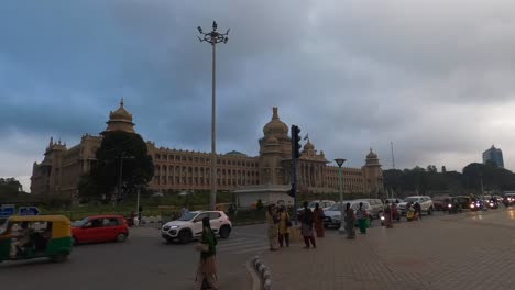 Bangalore,-Indien-–-Eine-Landschaft-In-Vidhana-Soudha-Mit-Menschen,-Die-In-Der-Dämmerung-Die-Straße-überqueren-–-Ruhige-Aufnahme