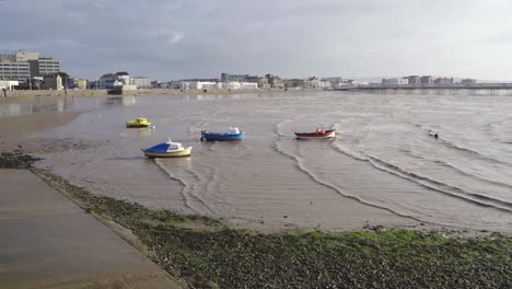 WESTON-SUPER-MARE,-SOMERSET,-UNITED-KINGDOM,-Small-fishing-boats-anchored-in-yellow-sand-beach