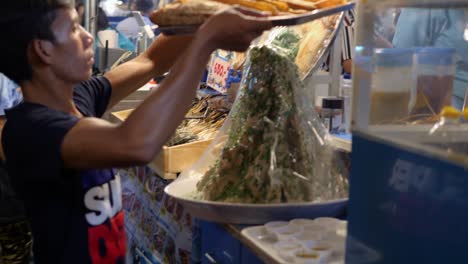 Man-delivers-tray-of-cooked-and-ready-to-eat-red-snapper-fish,-street-food-market