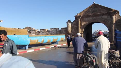 Steadicam-motion-moving-through-fishing-port-to-the-ancient-gate-of-Essaouira,-Morocco
