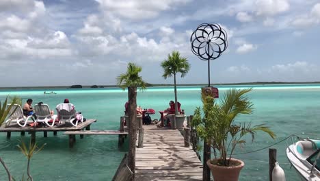 Tourists-Relaxing-on-a-Wooden-Dock-at-the-Beautiful-Bacalar-Lagoon-on-a-Summer-Day-in-Slow-Motion