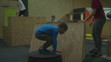 Kids-Playing-While-Jumping-To-The-Wooden-Platforms-At-Parkour-Gym-In-Cluj-Romania---Medium-Shot