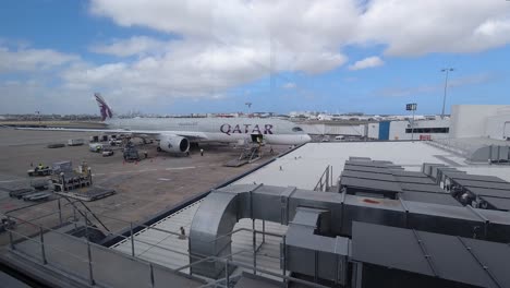 Avión-Cargando-Carga-En-El-Aeropuerto-De-Sydney---Personas-Que-Trabajan-Y-Equipos-De-Elevación-Transfieren-Artículos-Bajo-El-Brillante-Cielo-Nublado---Plano-General