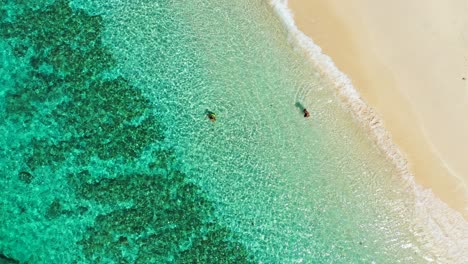 Insel-Boracay,-Philippinen---Tourist-Genießt-Die-Sommerferien,-Indem-Er-Unter-Der-Hitze-Der-Sonne-Auf-Dem-Grünen,-Flachen-Meer-Schwimmt---Luftaufnahme