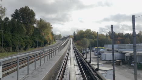 Ein-Zug-Fährt-Vom-Bahnhof-Zu-Den-Langen-Gleisen-über-Den-Hohen-Grünen-Bäumen,-Autos-Und-Gebäuden-Unter-Dem-Wolkigen-Himmel-In-Vancouver,-Kanada-–-Weitwinkelaufnahme