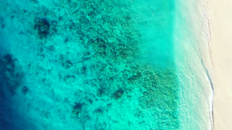 Beautiful-sea-texture-with-rocks-and-corals-over-seabed-seen-through-turquoise-clear-water-of-lagoon-washing-white-sand-of-exotic-beach,-copy-space