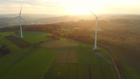 Drohnenflug-über-Grüne-Felder-Mit-Windrädern-In-Den-Sonnenaufgang