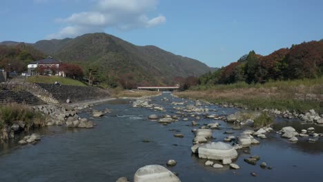 A-4k-dolly-tracking-shot-of-a-beautiful-river-with-mountains-in-the-background-during-a-cool-autumn-day-in-a-rural-onsen-village-in-Higashiomi,-Shiga-Prefecture,-Japan