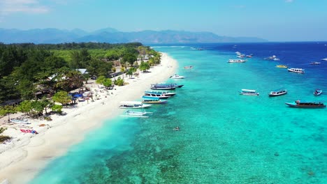 Paradise-exotic-beach-with-white-sand-in-front-of-calm-clear-water-of-turquoise-lagoon-full-of-touring-boats-sailing-around-Thai-islands