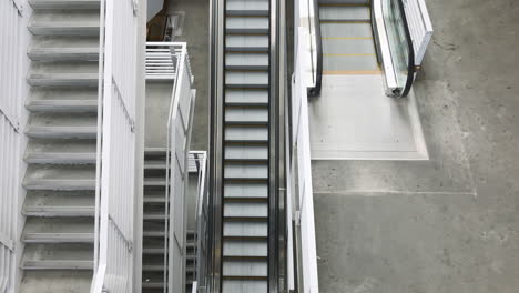 Top-view-of-a-stairwell-and-an-escalator-going-up,-handheld