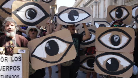Los-Manifestantes-Sostienen-Signos-De-Ojos-Durante-Una-Protesta-En-Las-Calles-De-Santiago