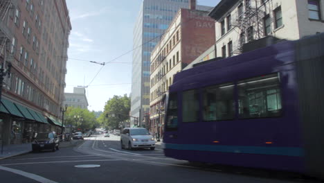 Light-rail-commuter-train-turns-through-an-intersection-in-downtown-Portland,-Oregon-on-a-sunny-day