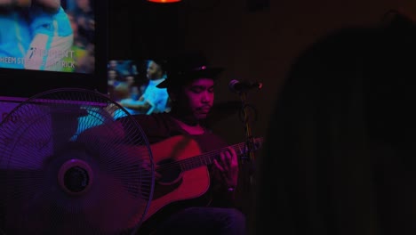 Hombre-Tailandés-Con-Sombrero-Tocando-La-Guitarra-En-Khaosan-Road-En-Bangkok,-Tailandia