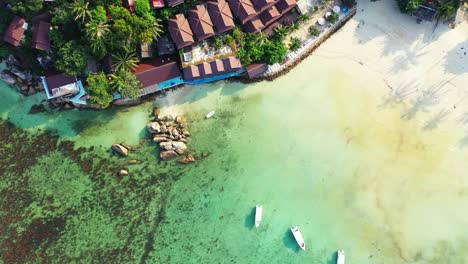 Boats-anchoring-on-shallow-lagoon-holiday-resort-and-beautiful-cliffs-on-shoreline-of-tropical-island-in-Thailand
