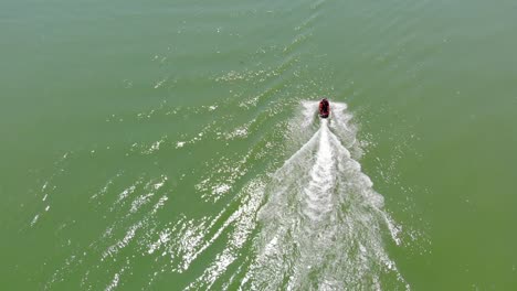 Wave-runner-rider-exits-into-the-Adriatic-sea-from-Porto-Santa-Margherita-harbor,-Aerial-drone-flyover-shot