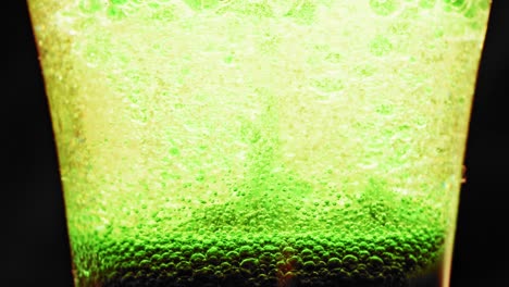 Makroaufnahme-Funkelnder-Grüner-Blasen,-Die-Sich-In-Einem-Glas-Mit-Hellem-Hintergrund-Nach-Oben-Bewegen