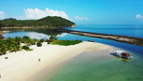 Tranquil-bay-with-calm-clear-water-of-shallow-lagoon-washing-white-sand-of-exotic-beach-with-palms-on-tropical-island-in-Thailand