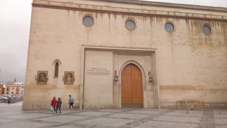 Tilt-down,-people-walk-by-Santuario-de-los-Gitanos-church-in-Seville,-Spain