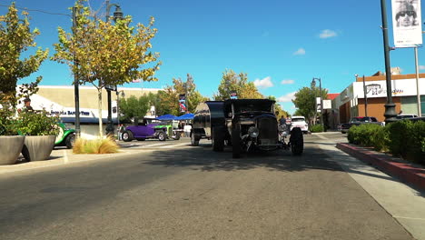 Black-low-rider-hot-rod-tows-trailer-through-car-show,-slow-motion