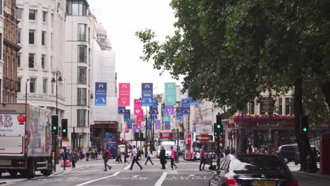 Street-with-people-and-double-deckers-in-London,-typical-day-in-capital-city-of-United-Kingdom