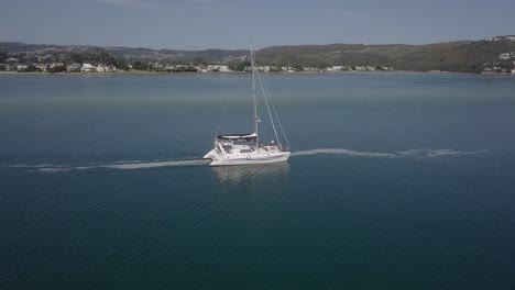 Friends-on-catamaran-sailboat-motor-slowly-across-lagoon-out-to-sea