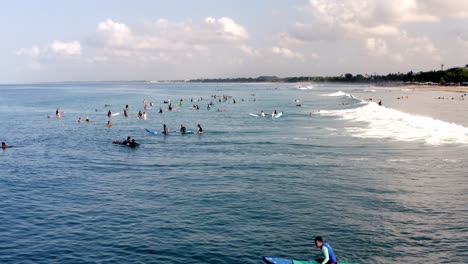 Surfers-ride-waves-on-a-popular-international-surfing-spot-on-the-island,-Aerial-drone-flyover-low-altitude-shot