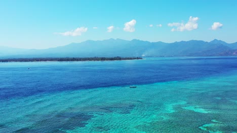 Peaceful-sea-scenery-with-blue-turquoise-colors-of-beautiful-calm-water-surface-over-coral-reefs,-blue-sky-with-white-clouds-in-Indonesia