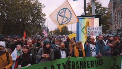 Pan-Of-Extinction-Rebellion-Protestiert-Auf-Der-Straße-In-Amsterdam-Mit-Menschen,-Die-Sprechchöre-Rufen-Und-Fahnen-Schwenken