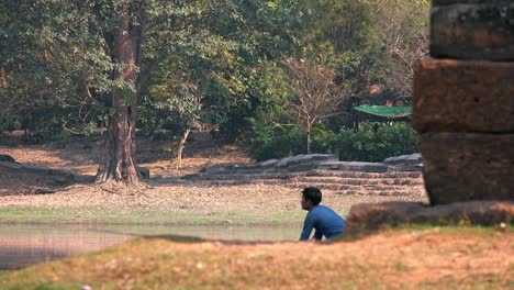 Asiatischer-Fischer-Wirft-Seine-Rute-In-Den-Wassergraben-Von-Angkor-Wat-In-Kambodscha