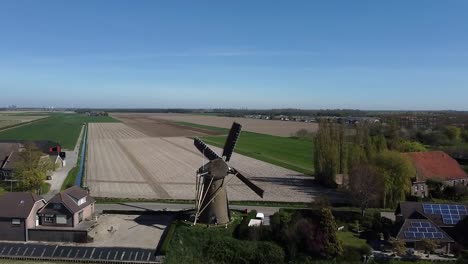 Fliegen-Mit-Einer-Drohne-über-Eine-Sich-Drehende-Holländische-Windmühle-Mit-Segeln-Am-Zaun-Der-Rotorblätter