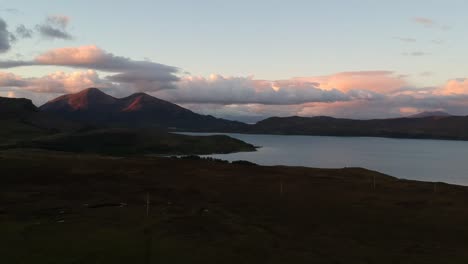 Panning-drone-shot-of-Scottish-mountain-lake-and-cloudscape-at-golden-hour