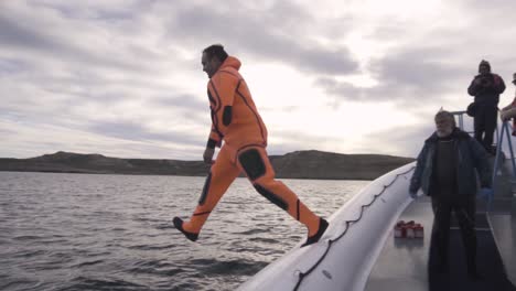 Un-Hombre-Con-Traje-De-Inmersión-Naranja-Salta-Al-Agua-Como-Parte-Del-Entrenamiento-Náutico-En-El-Mar-Patagónico---Cámara-Lenta