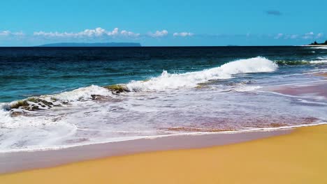 HD-Hawaii-Kauai-slow-motion-pan-left-to-right-from-ocean-waves-coming-in-on-the-beach-with-an-island-in-the-distance-to-the-beach-on-frame-right-and-ocean-waves-crashing-in-from-left-to-right