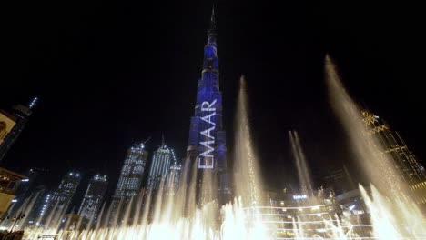 Sensational-nighttime-Dubai-attraction:-scenic-view-of-water-fountain-display-and-lights-at-base-of-Burj-Khalifa,-static-low-wide-angle