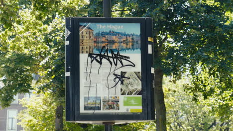 A-tourist-sign-about-the-history-of-The-Hague-in-the-city-centre,-smothered-in-graffiti