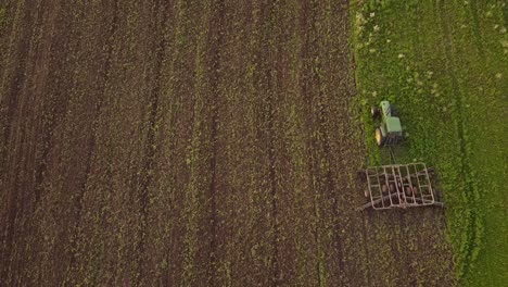 Farm-Tractor-Working-In-The-Wide-Field-Tilling-The-Soil-In-Monroe-County,-Michigan,-USA---Aerial-Shot