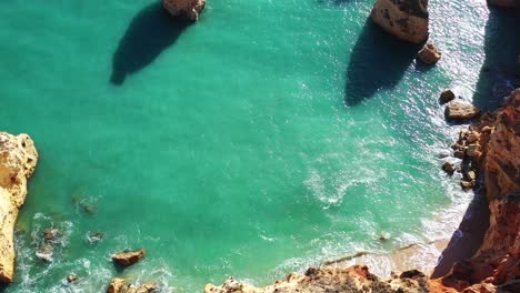 Fallen-eroded-rock-formations-in-Marinha-Beach-south-of-Portugal,-Aerial-top-view-turning-shot