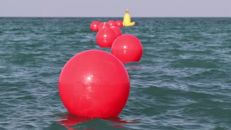 Eine-Reihe-Roter-Bojen,-Die-Aus-Sicherheitsgründen-In-Den-Meereswellen-Schwimmen