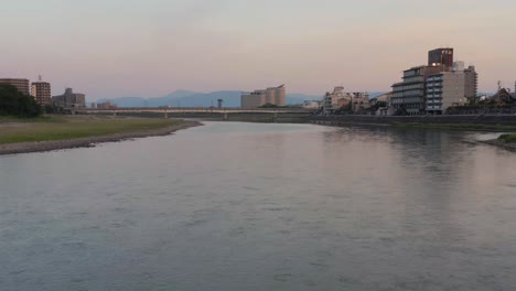 Slowly-flying-along-Nagara-river,-tilt-to-reveal-Gifu-Japan-at-sunrise