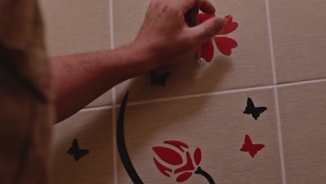 Man-Glues-Decorative-Flowers-From-Adhesive-Film-On-The-Wall