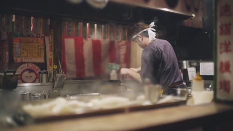 Chef-Cocinando-Una-Comida-Deliciosa-Para-Los-Clientes-En-Un-Izakaya-Tradicional-Japonés-Por-La-Noche-En-Kyoto,-Japón