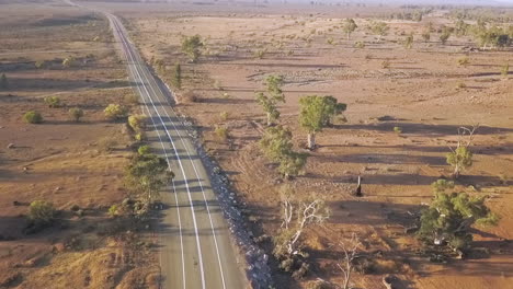 Drone-lifting-up-over-road-to-reveal-Australian-outback-landscape