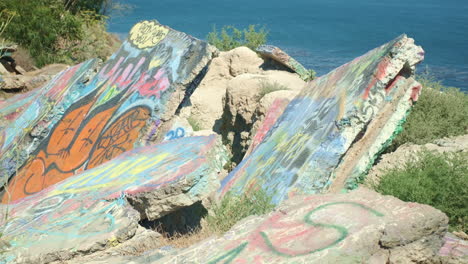 Mit-Graffiti-Bedeckte-Felsen-Mit-Blick-Auf-Den-Blauen-Pazifischen-Ozean-Bei-Tag