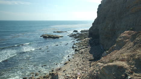Waves-Calmly-Crashing-into-Rocky-Shore-by-Rugged-Cliff-in-Daytime,-Quintessential-California-Coast