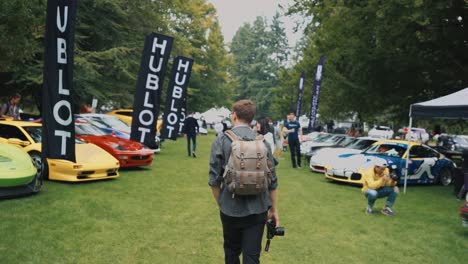 Man-Walking-Down-the-Middle-of-Rows-of-Supercars-at-Luxury-Car-Show