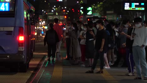 Koreaner-Mit-Gesichtsmaske-Stehen-An-Der-Bushaltestelle-Im-Bahnhof-Gangnam,-Der-Innenstadt-Bei-Nacht,-Covid-19,-Seoul,-Südkorea