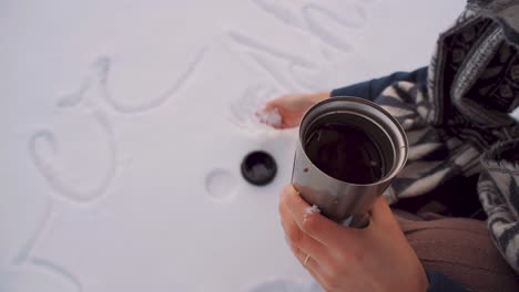 Female-Picking-Up-Snow-And-Putting-In-Flask-Drink-Outside