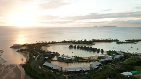 Epic-bright-sunset-at-Marriot-Resort-in-Fiji,-paradise-coast-with-lagoon,-aerial